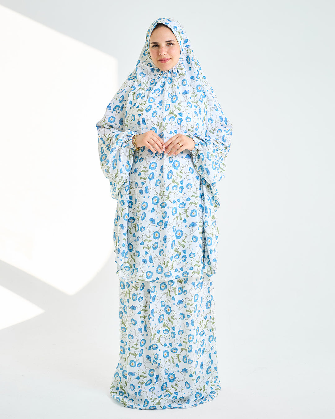 Woman wearing a floral dress with a matching headscarf on a white background